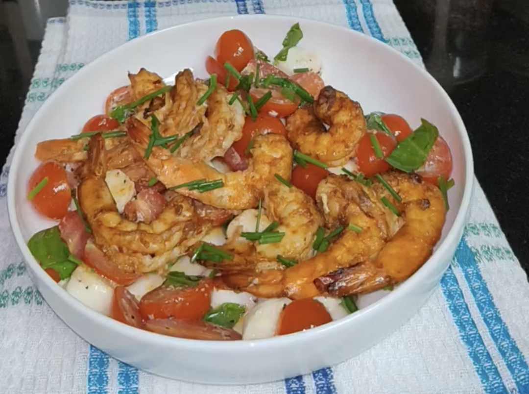 Air fryer shrimp seasoned with paprika and chilli flakes, served with a fresh salad and garnished with chopped chives
